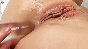 Slender nympho rubs her snatch and drills her ass with a glass dildo